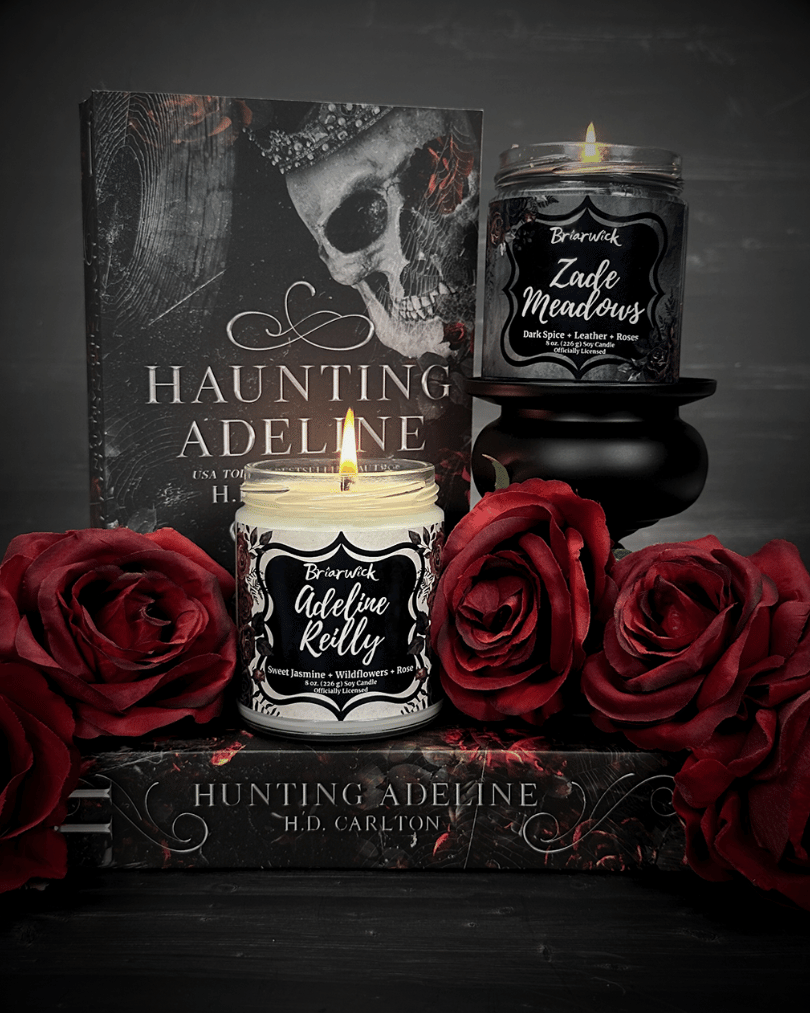 Haunting Adeline Book with Black Zade Meadows candle and White Adeline Reilly candle in front of it.