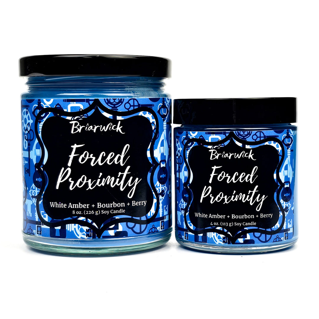 Forced Proximity 8oz & 4oz steel blue candles with blue lock & key designs on a white background