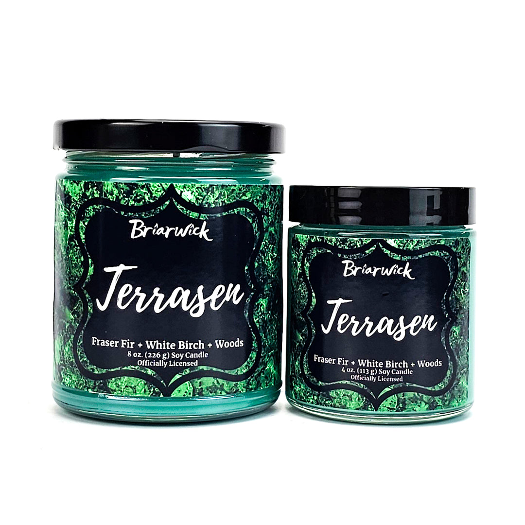 two jars of green and black candles on a white background