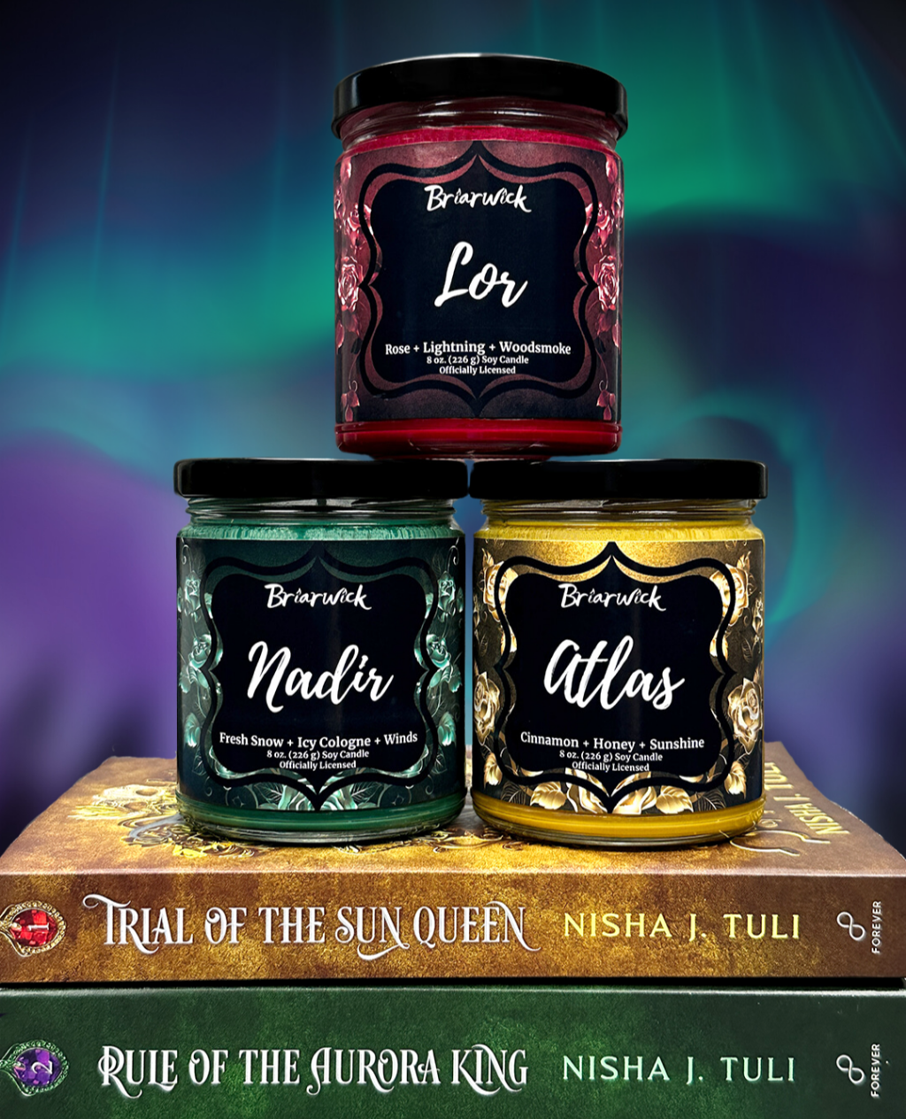 Three candles stacked on top of each other with a book titled 'Rule of the Aurora King' in the background.