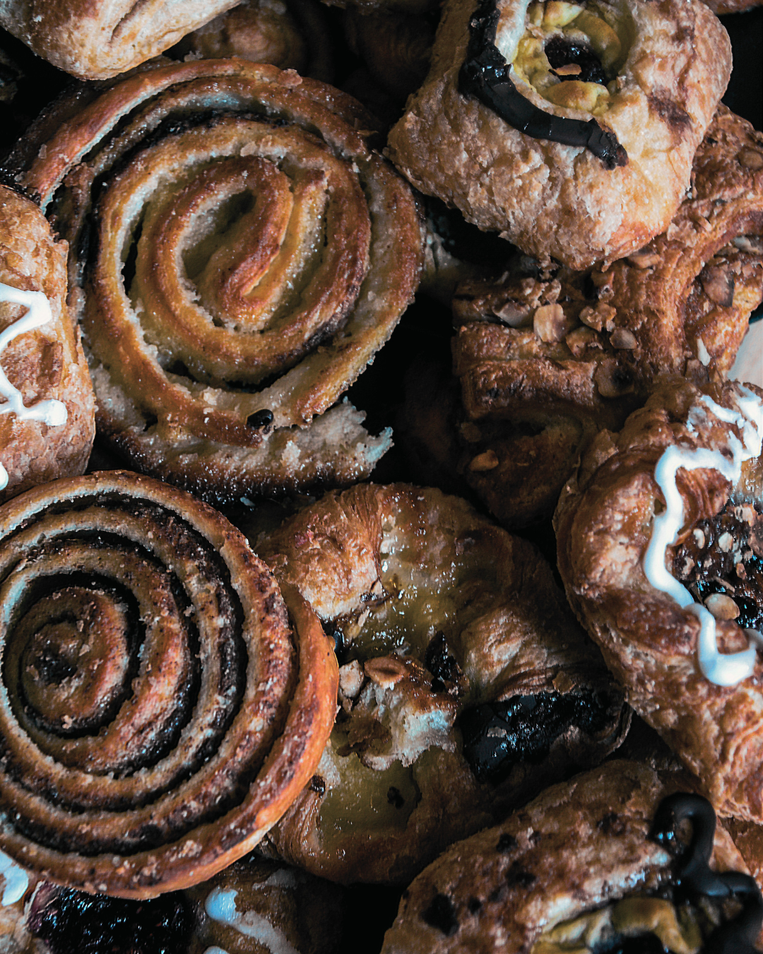 Assorted pastries including cinnamon rolls and cookies on a wooden surface