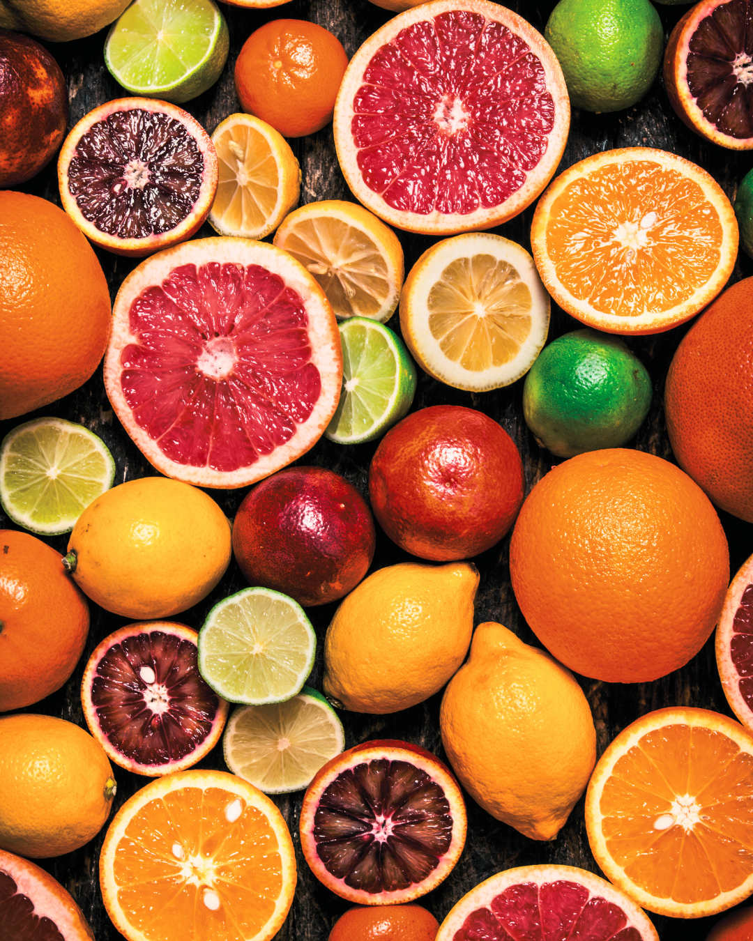Assorted citrus fruits including oranges, lemons, and blood oranges on a dark background