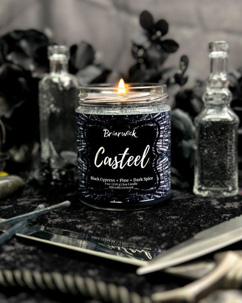 Candle with 'Casteel' branding on a dark surface with decorative elements.