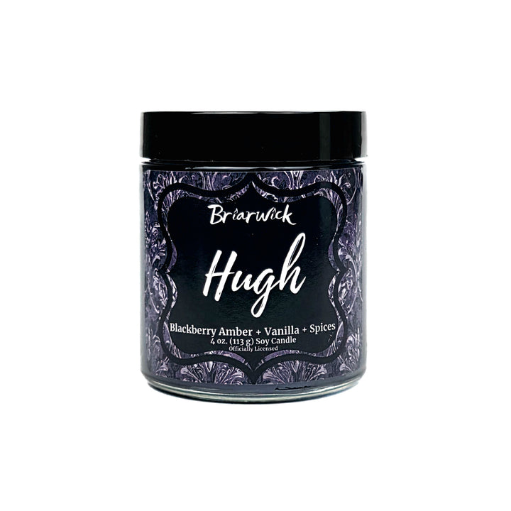 A jar candle labeled 'Briarwick Hugh' with a black lid and a dark purple label featuring white script and decorative border, on a plain white background.