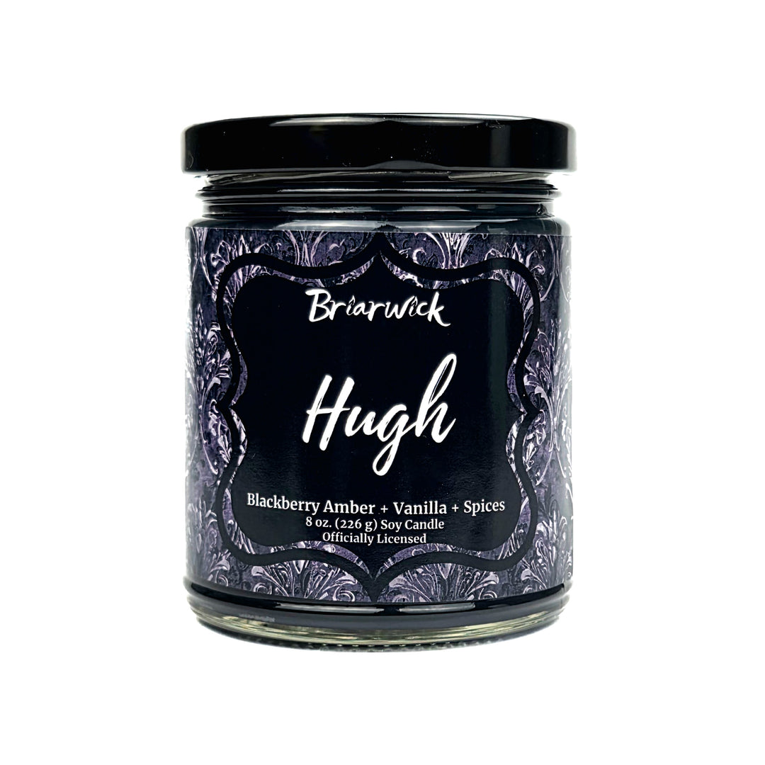 A jar candle labeled Briarwick Hugh, featuring a black lid and a dark label with purple ornate patterns, on a plain white background.