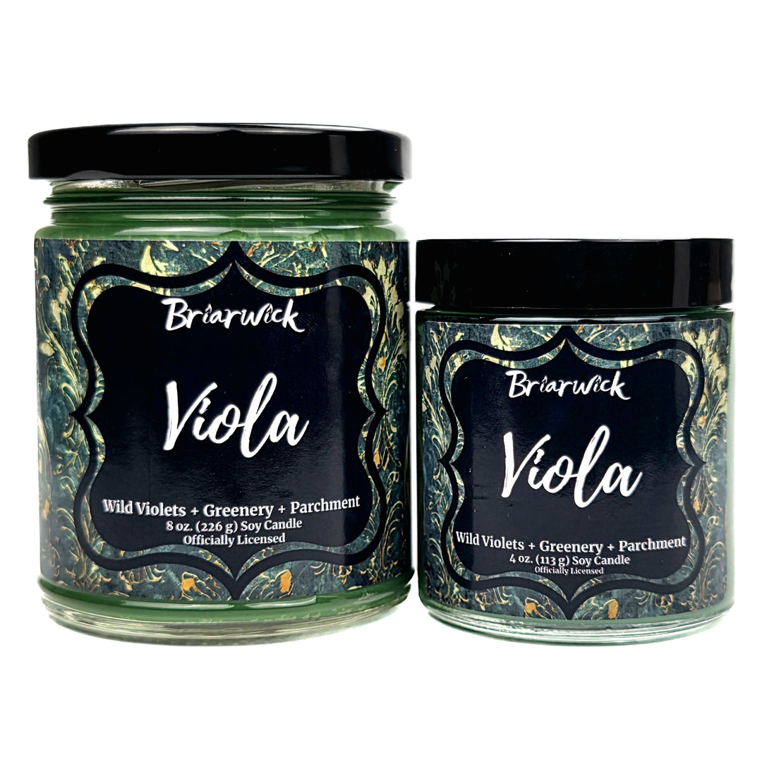 Two Briarwick Viola scented soy candles in glass jars with black lids, displayed side-by-side on a white background. The left jar is 8 oz and the right jar is 4 oz, both featuring green wax and matching dark green and gold marbled labels with black central labels.