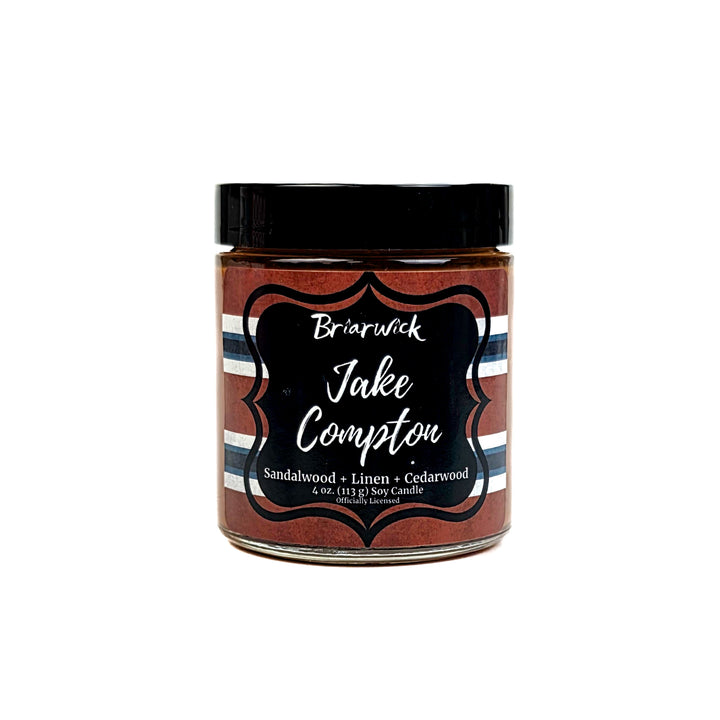 Jar of Briarwick Jake Compton candle with striped label on a white background