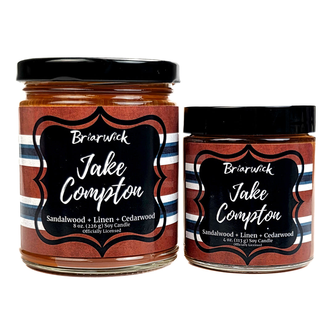 Two jars of Briarwick Jake Compton candles with striped labels on a white background