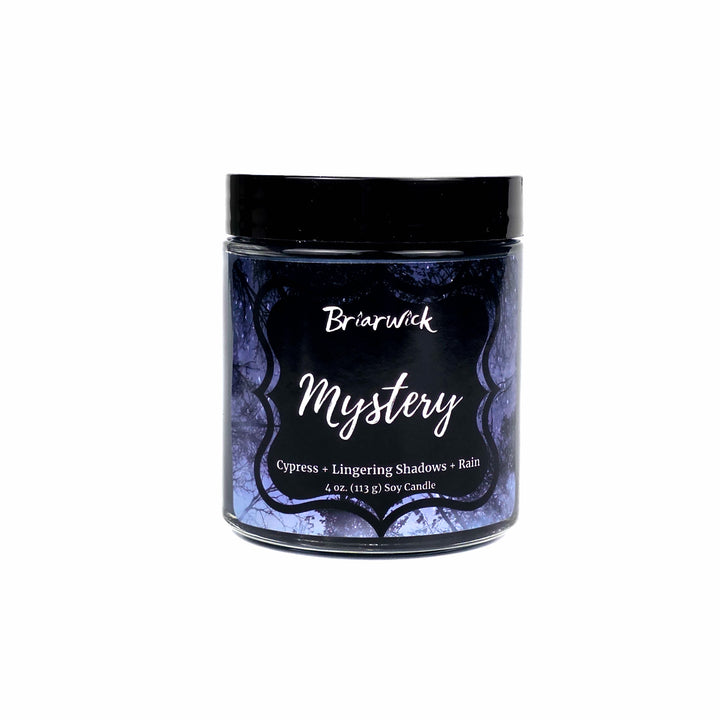 A 4 oz soy candle in a clear glass jar with a black lid and a dark blue label featuring white text that reads 'Briarwick Mystery' set on a white background.