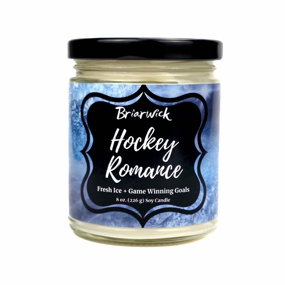 An 8 oz soy candle in a clear glass jar with a black lid on a white background, featuring a blue and white icy label with a black frame that reads 'Briarwick Hockey Romance'.