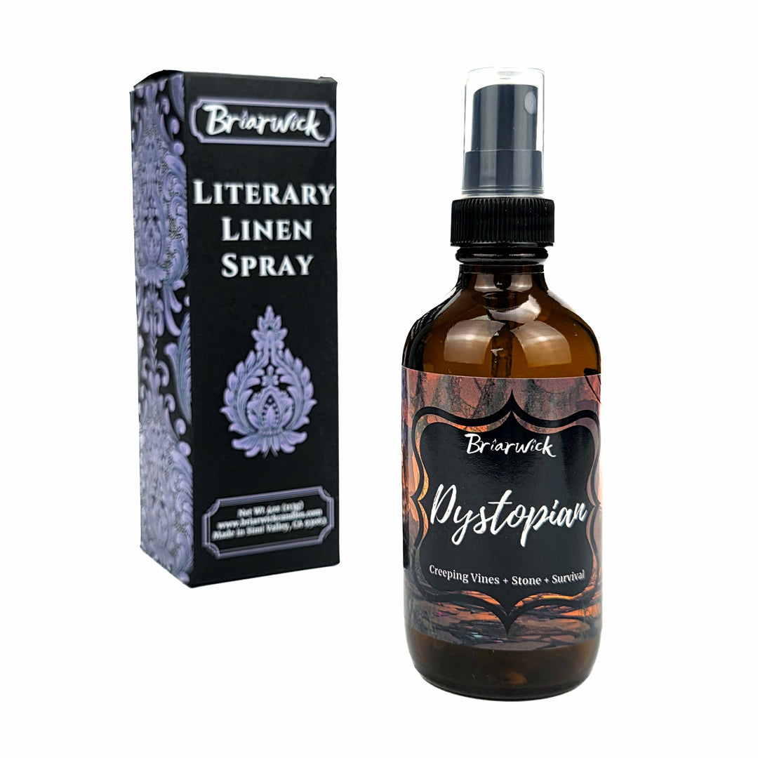 An amber glass spray bottle labeled 'Briarwick Dystopian Literary Linen Spray' stands next to its black and lavender patterned retail box on a plain white background.