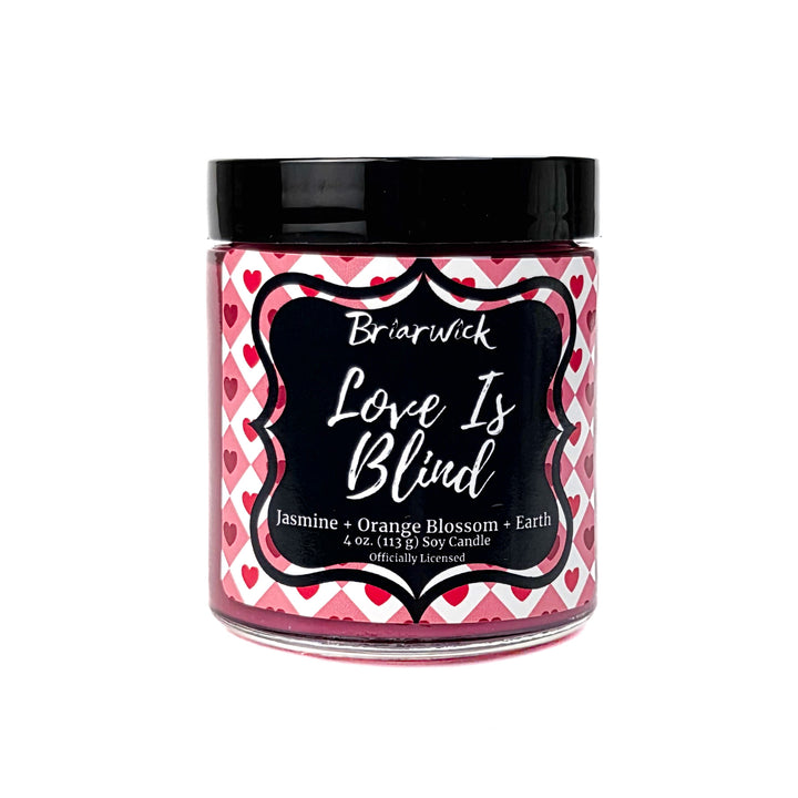 A red Love is Blind 4 oz candle by Briarwick on a white background