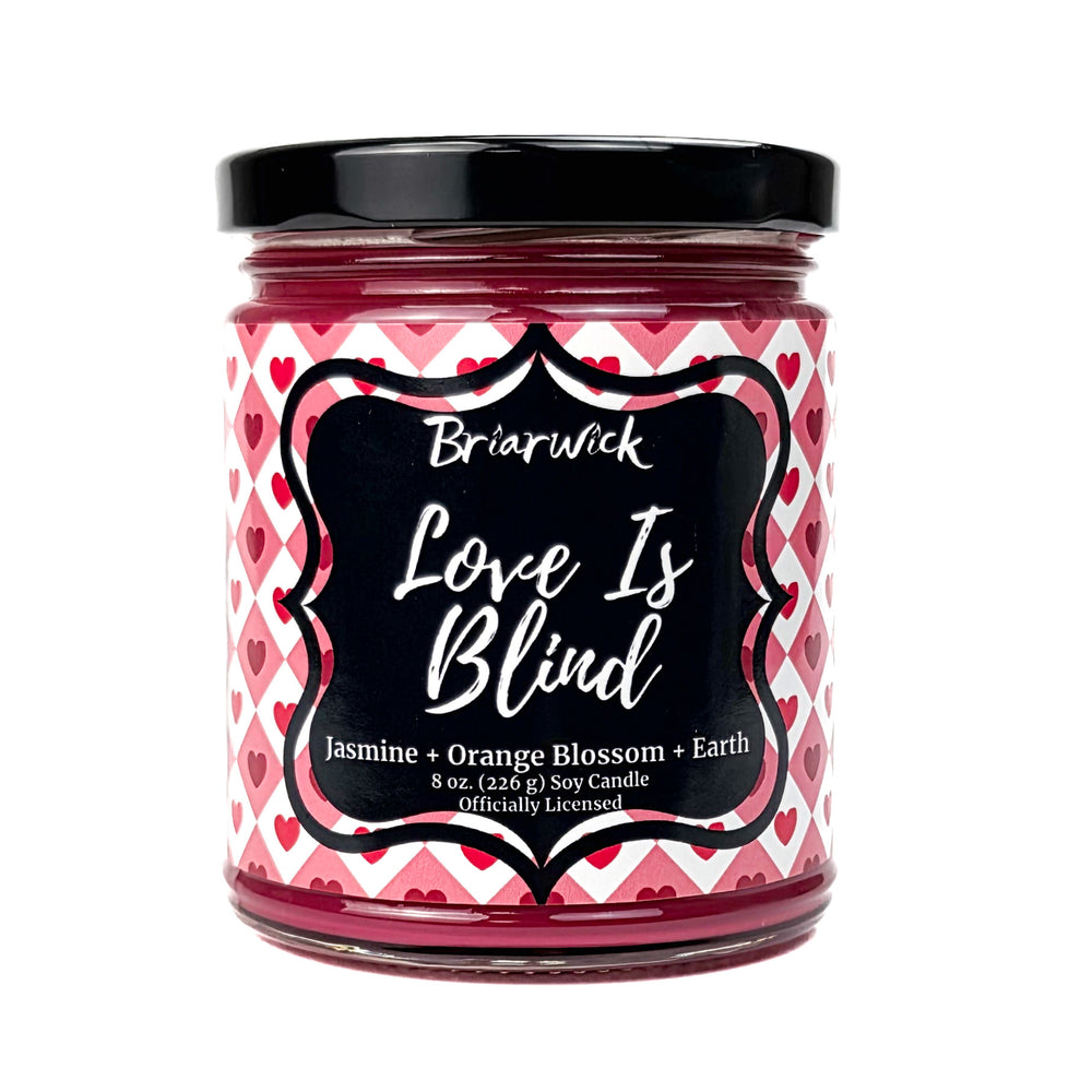 A red Love is Blind 8 oz candle jar by Briarwick on a white background
