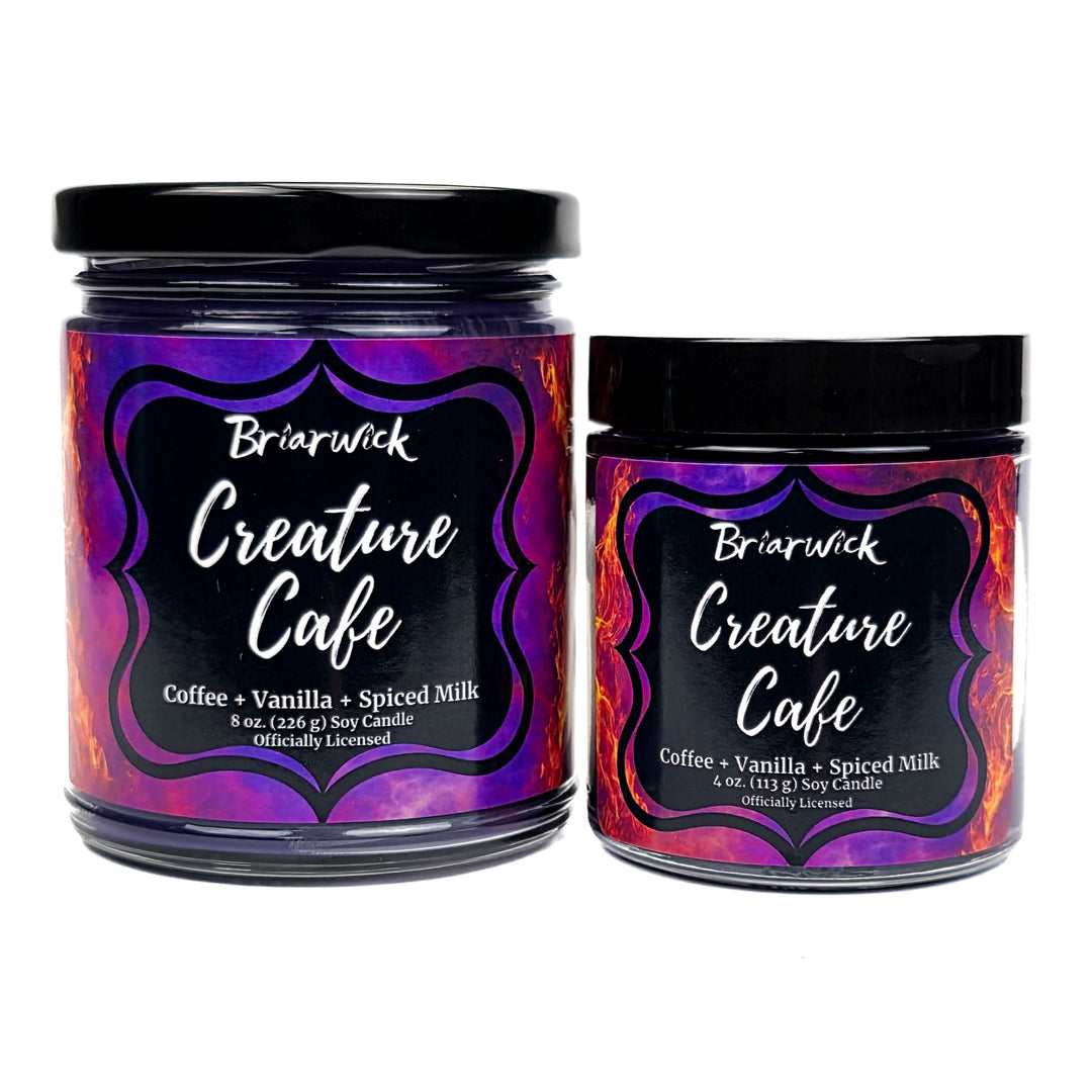 Two candles from Briarwick Creature Cafe with colorful labels on a white background
