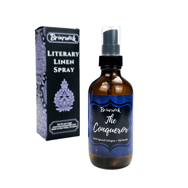 Briarwick Literary Linen Spray bottle and packaging on a white background. Amber bottle has blue label with scent name The Conqueror 
