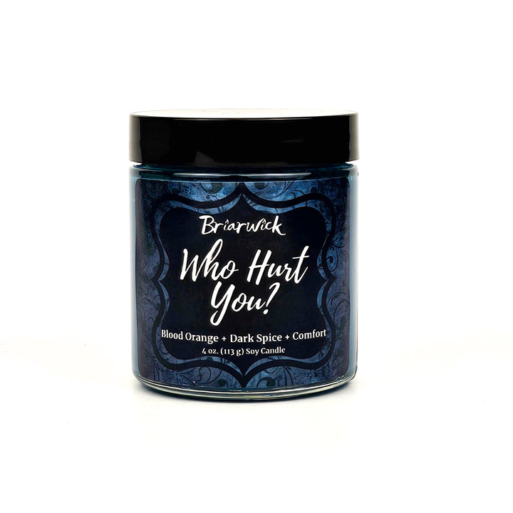 Who Hurt You? 4oz dark teal candle with blue ornamental design on a white background