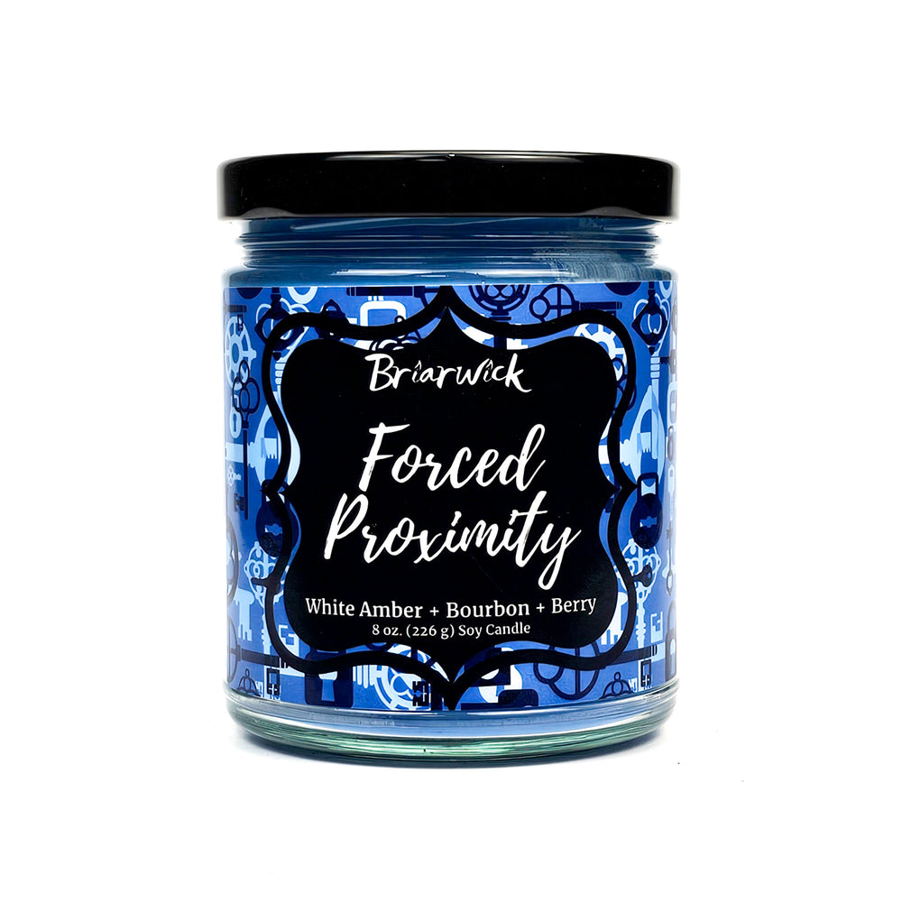 Forced Proximity 8oz steel blue candle with blue lock & key design on a white background