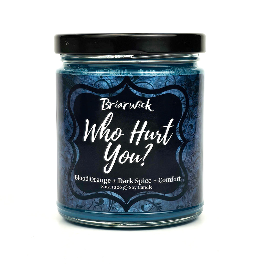 Who Hurt You? 8oz dark teal candle with blue ornamental design on a white background