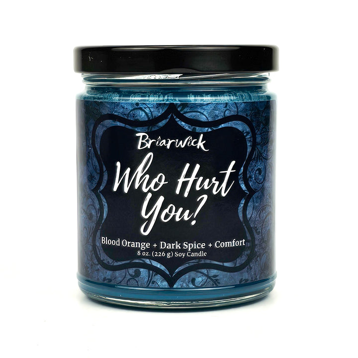 Who Hurt You? 8oz dark teal candle with blue ornamental design on a white background