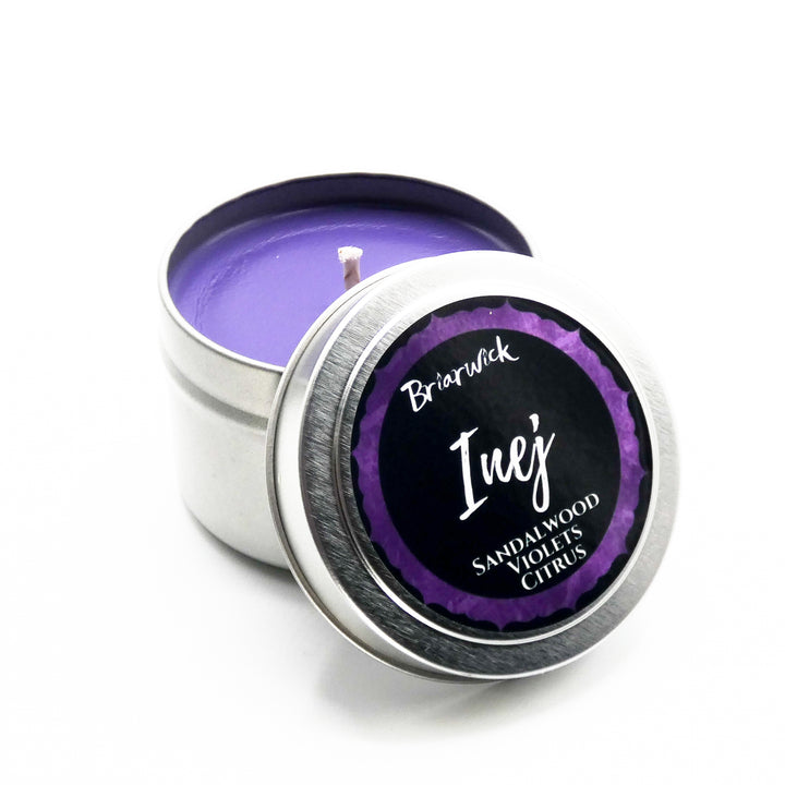 a tin with a purple candle inside of it
