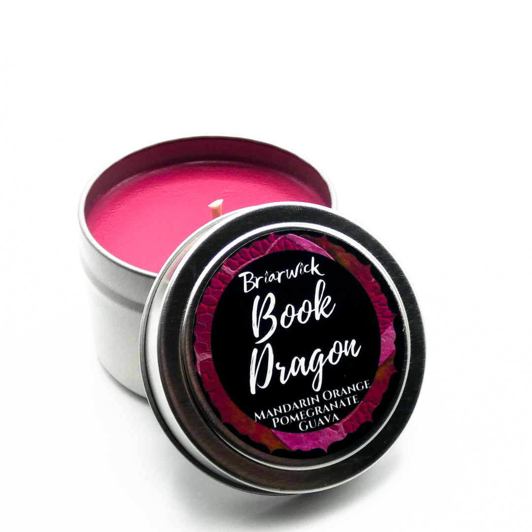 a pink candle in a tin on a white surface